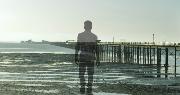 Against the background of dreary Southend pier, a young man is walking away and fading out